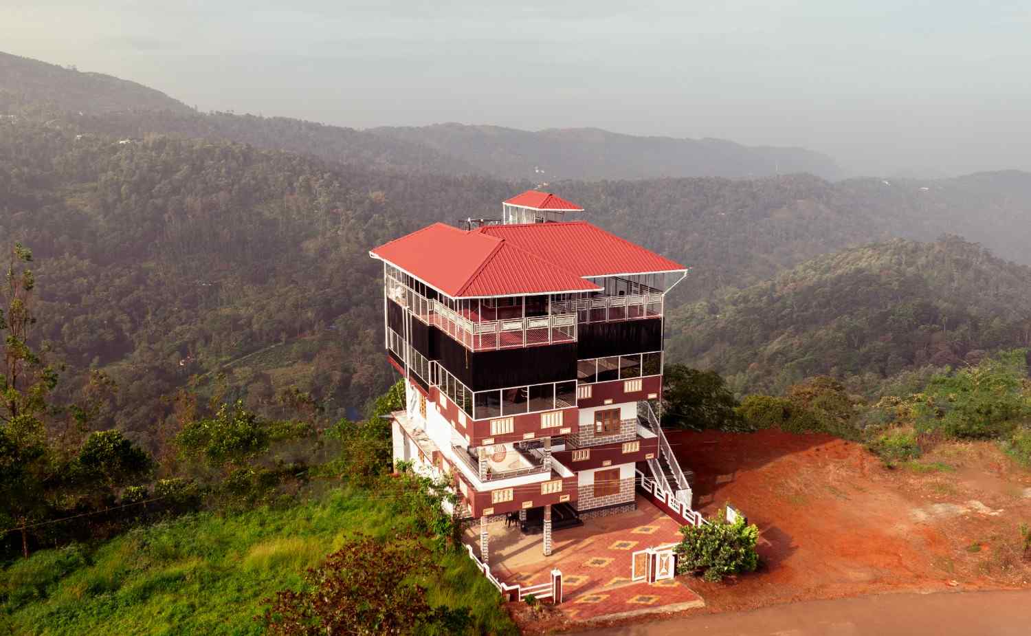 Aerial view of Malabar House Homestay surrounded by green hills in Idukki